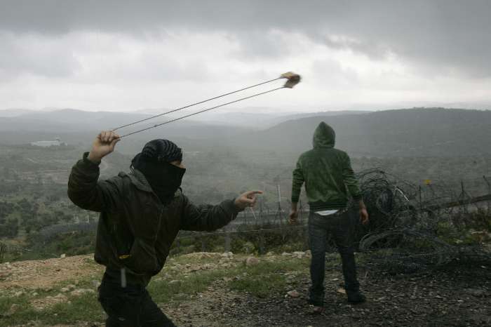 Palestino usa um estilingue para atirar pedras nos soldados israelitas, em Ramallah