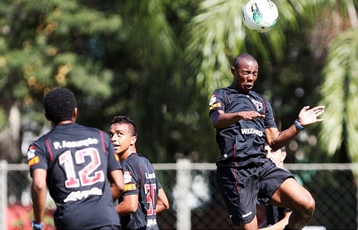Luis Fabiano corre pelo campo, enquanto companheiros treinam com a bola no CT do São Paulo