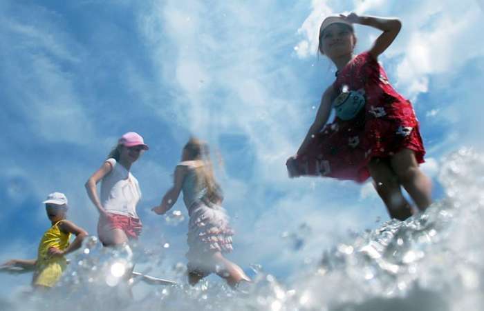 Com o calor na Ucrânia, crianças brincam e se refrescam na fonte do centro da cidade de Kiev