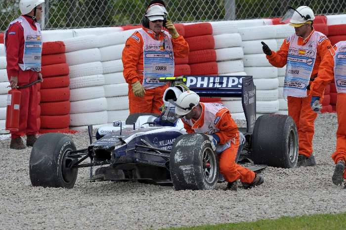 Fiscais tentam tirar o Williams de Hulkenberg da caixa de brita após batida no treino na Espanha