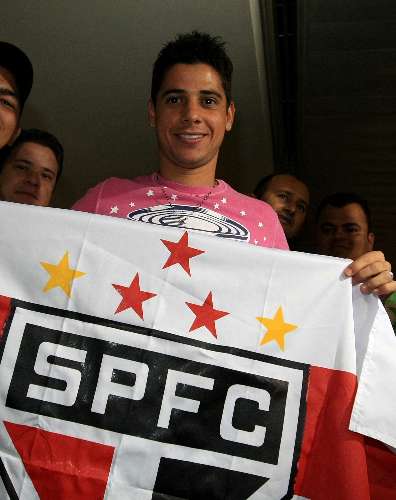 Na chegada a São Paulo, o lateral-direito Cicinho posa com a bandeira do time tricolor