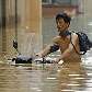 Chinês carrega sua moto em meio a rua inundada de Xianning, na China Chinês carrega sua moto em meio a rua inundada de Xianning, na China