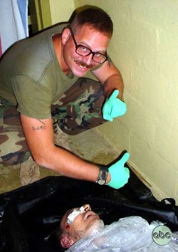 Militar americano posa para foto junto a prisioneiro torturado na prisão de Abu Ghraib, no Iraque