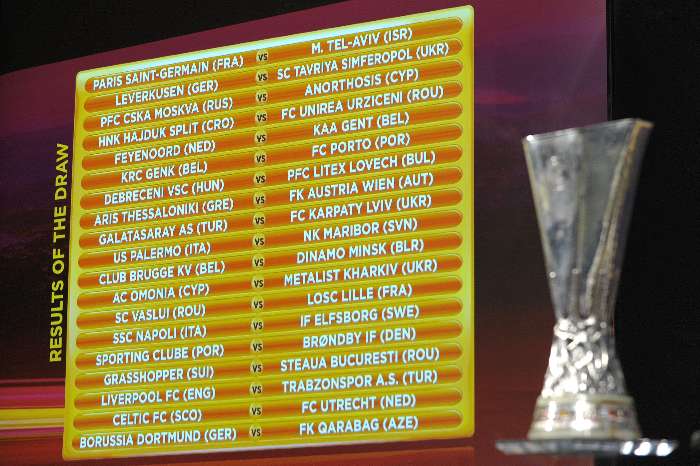 O troféu de campeão da Liga Europa ao lado do painel com os duelos eliminatórios, após sorteio
