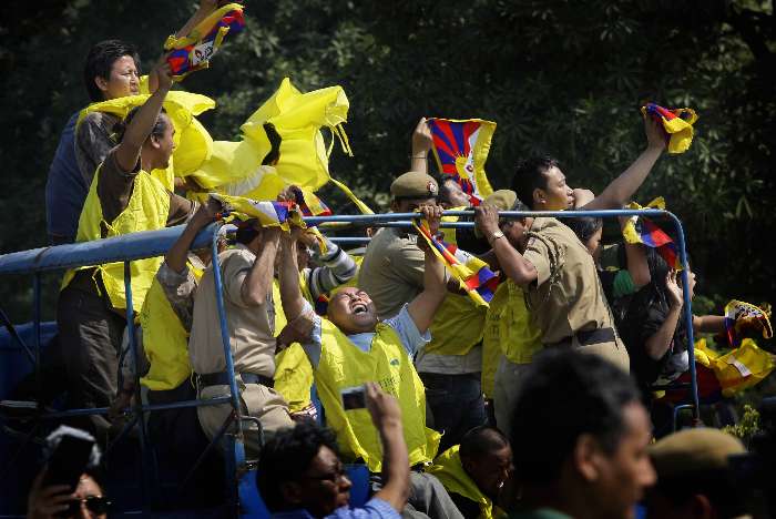 Tibetanos exilados gritam de uma van policial em protesto ao governo chinês