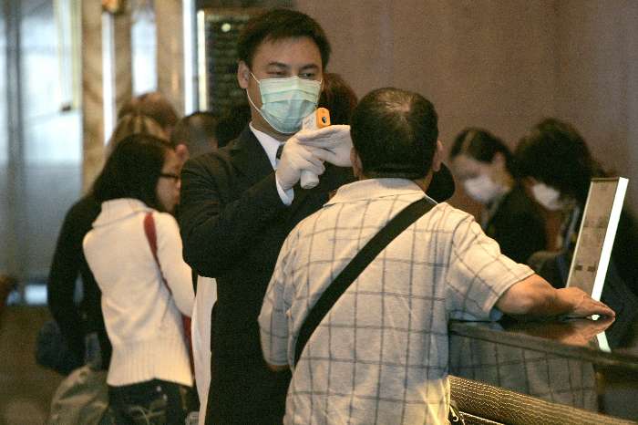 Funcionário de hotel mede temperatura de hóspede antes de sua entrada em Hong Kong