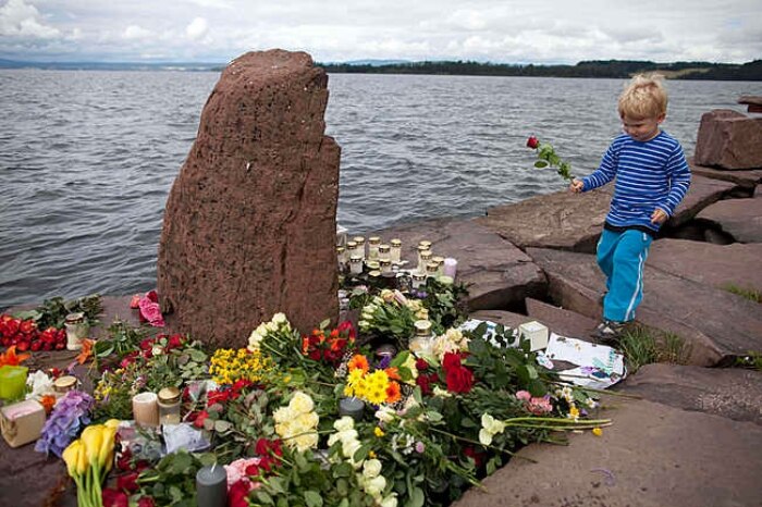 Criança coloca flor em monumento improvisado em memória aos ataques ocorridos em Oslo na sexta-feira