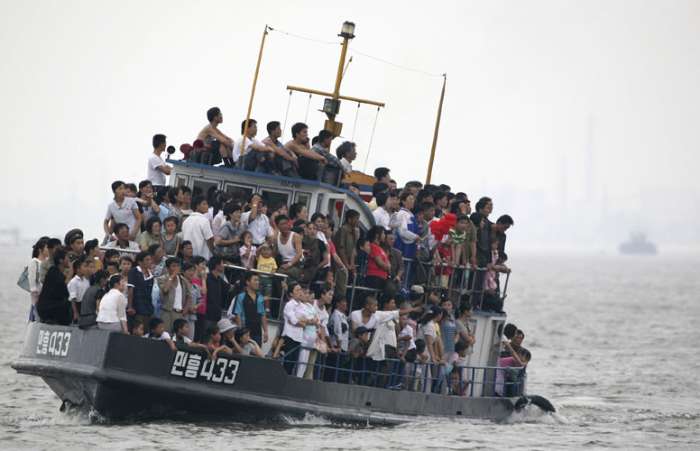 Norte coreanos observam barco de turistas chineses na cidade de Sinuiju, Coreia do Norte