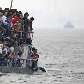Norte coreanos observam barco de turistas chineses na cidade de Sinuiju, Coreia do Norte