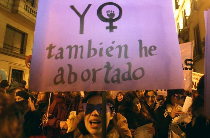 Mulher carrega cartaz em demonstração ao Dia Internacional da Mulher