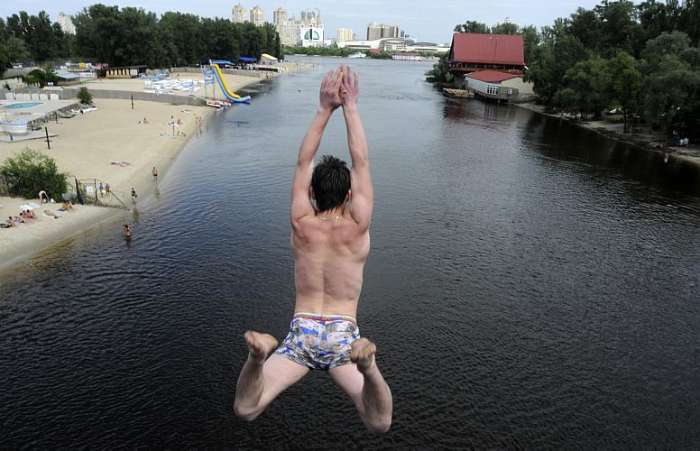 Jovem pula da ponte Venetian no rio Dnieper, em Kiev, Ucrânia