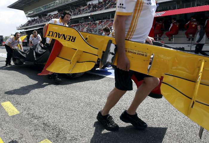 Mecânicos carregam os pedaços da Renault de Vitaly Petrov após batida no treino livre na Espanha