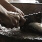 Vendedor prepara peixe para venda no mercado informal de Kuala Lumpur, na Malásia