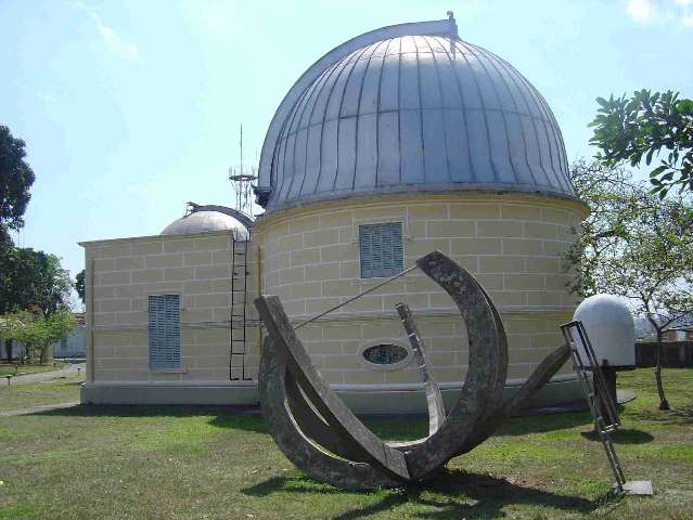 Relógio de sol ao lado de cúpula de observação no campus do Observatório Nacional