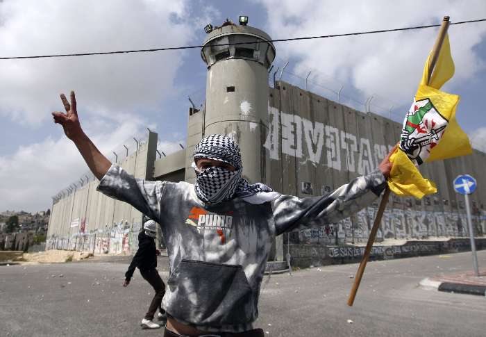 Jovem palestino em frente a controversa barreira israelita durante demostração contra as restrições