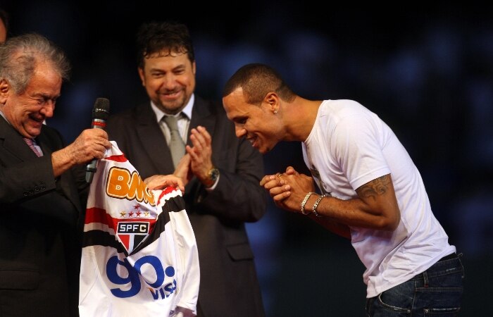 Luís Fabiano esfrega as mãos para receber a camisa do São Paulo do presidente Juvenal Juvêncio