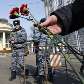 Oficiais russos observam  homem vendendo flores na frente da estação Park Kultury 