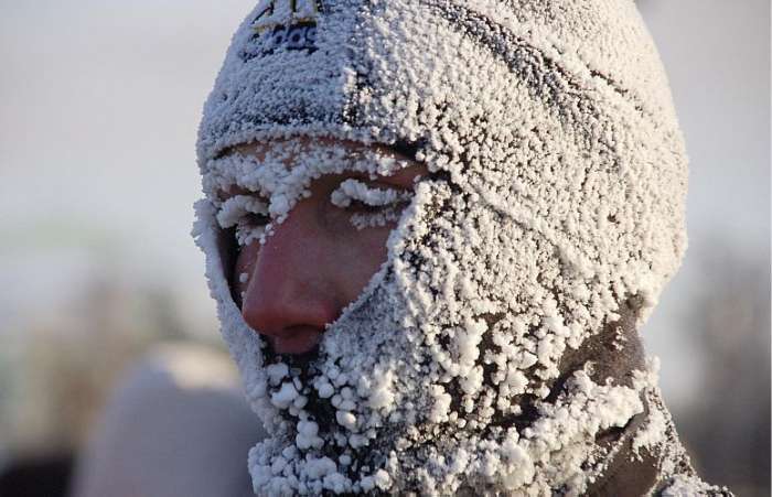 Homem cobre o rosto para se proteger do frio e da neve em Krasnoyarsk, na Rússia