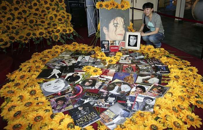 Chinesa posa com flores e fotos de Michael Jackson, em exposição de Shanghai