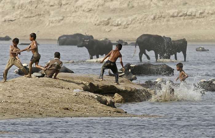 Meninos brincam de castelo no rio Tigris, em Bagdá, Iraque 