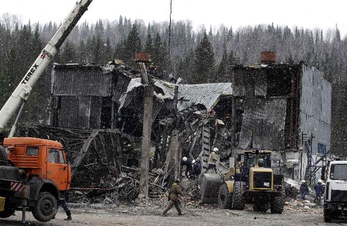 Trabalhadores ao lado dos destroços da mina que explodiu na Sibéria, Rússia