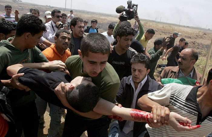 Palestinos ajudam jovem ferido durante enfrentamento com soldados israelitas em Gaza