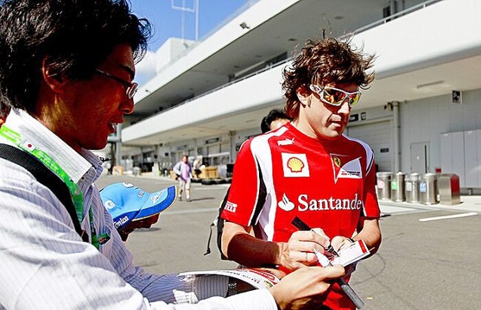Fernando Alonso, piloto da Ferrari, dá atenção para fã