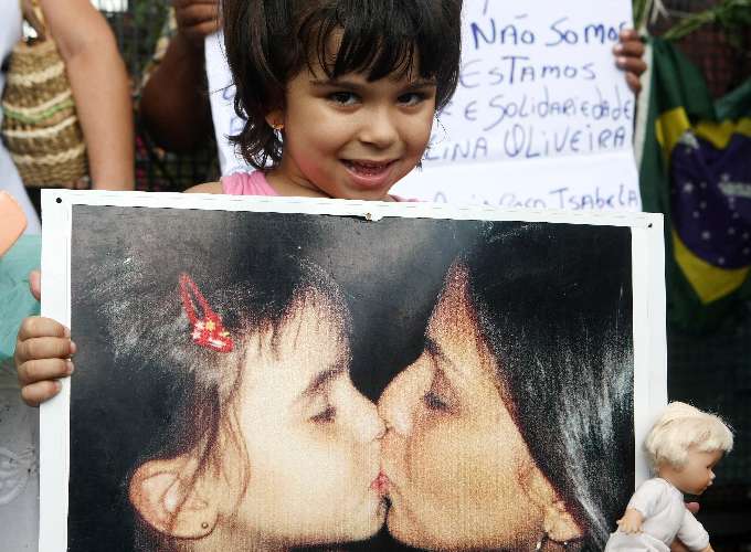 Criança segura foto de mãe e filha ao lado de fora do Fórum durante o o júri do caso Isabella