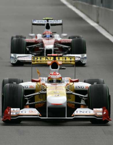 Fernando Alonso, da Renault, chega aos boxes à frente de Timo Glock, da Toyota