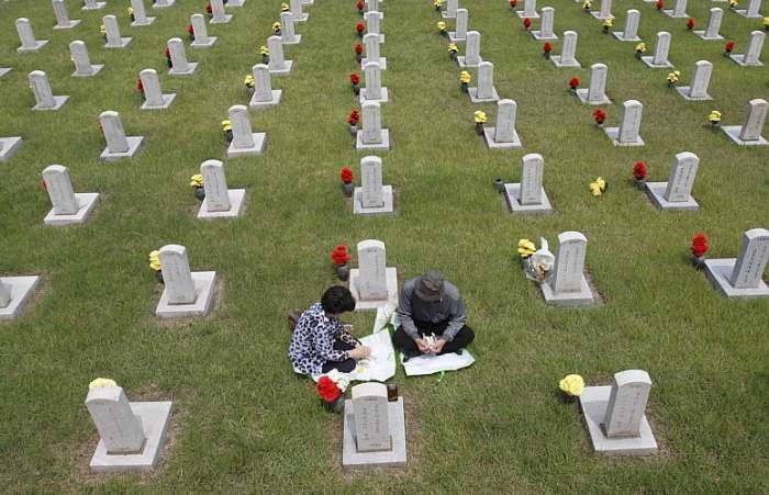 Parentes visitam mortos no cemitério; guerra nunca foi encerrada formalmente, apenas por uma trégua