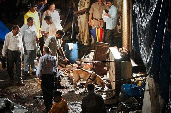 Polícia usa cão farejador no local de uma explosão no Bazar Jhaveri, em Mumbai, nesta quarta, 13