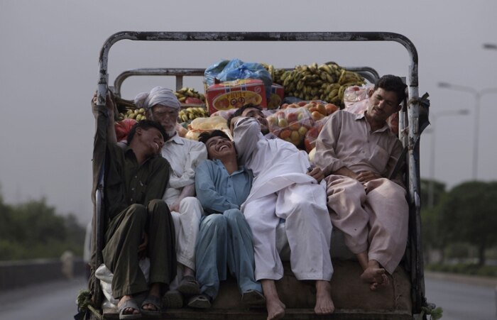 Paquistaneses viajam em veículo de transporte para frutas e legumes em Islamabad