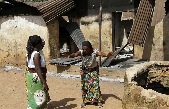 Mulher chora em frente a prédios queimados na vila de Dogo Nahawa, Nigéria