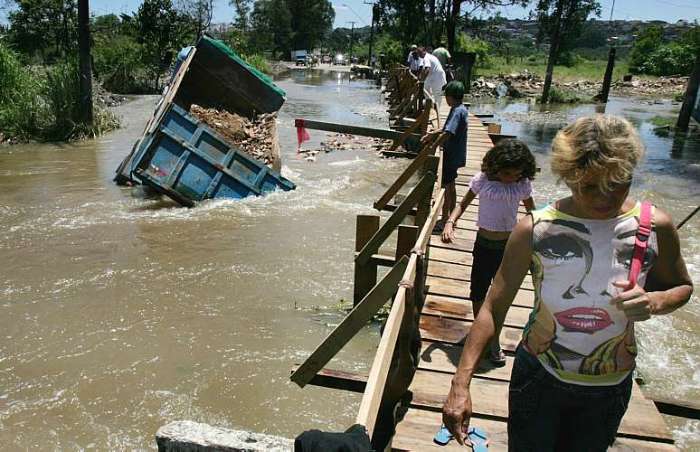 Caminhão tomba ao tentar passar por área alagada em Guarulhos, onde passarela foi construída