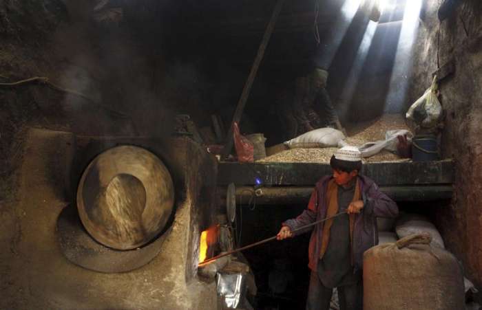 Afegão trabalha na preparação de pipoca em fábrica de Cabul; economia do país enfrenta problemas