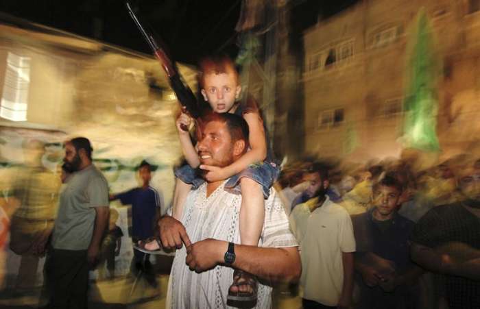 Menino carrega arma de brinquedo durante a celebração do Hamas