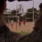 Buraco em muro, onde observa-se meninos jogando futebol em  campo de areia. Atibaia, SP 11-09-2011