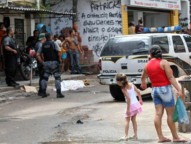 Menina observa corpo de um dos mortos durante confronto da PM com traficantes na Rocinha