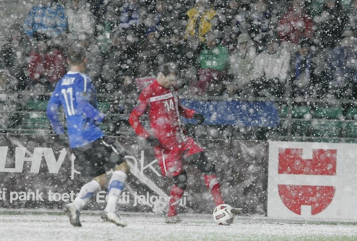 Jovanovic, da Sérvia, carrega a bola antes da chegada de Enar Jaager, da Estônia, no 1 a 1 sob neve