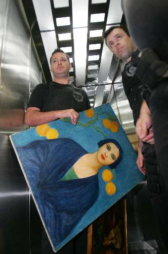 Policial carrega o quadro de Tarsila do Amaral que foi roubado da família Maksoud