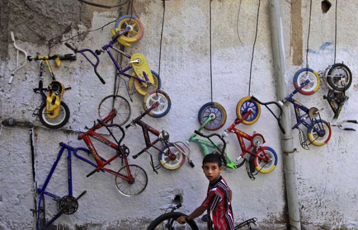 Menino palestino compra  pneu para sua bicicleta em loja de segunda mão de Al-Amari, Palestina
