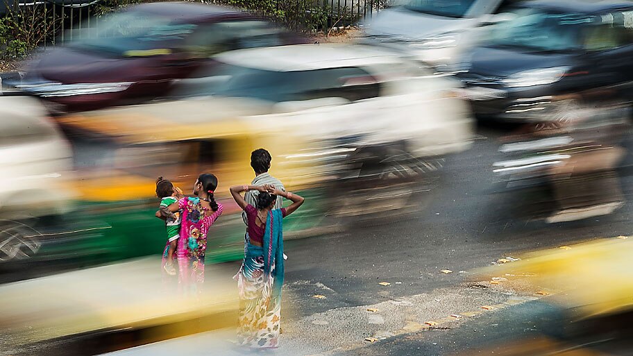 Roberto Schmidt / AFP   -  Indianos esperando ônibus em meio ao intenso tráfego de veículos em Nova Délhi. Foto: Roberto Schmidt / AFP  
