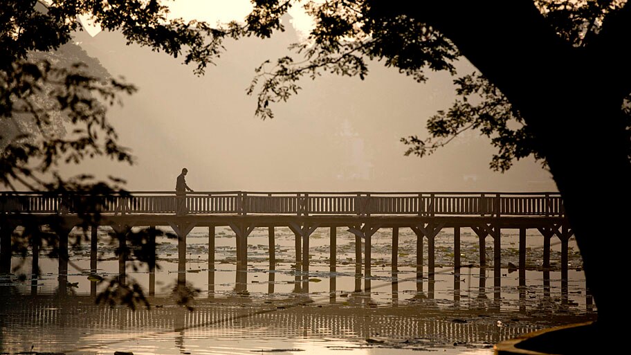  - Homem anda em uma ponte de madeira ao amanhecer, no lago Kandawgyi, em Myanmar. Foto: Gemunu Amarasinghe / AP