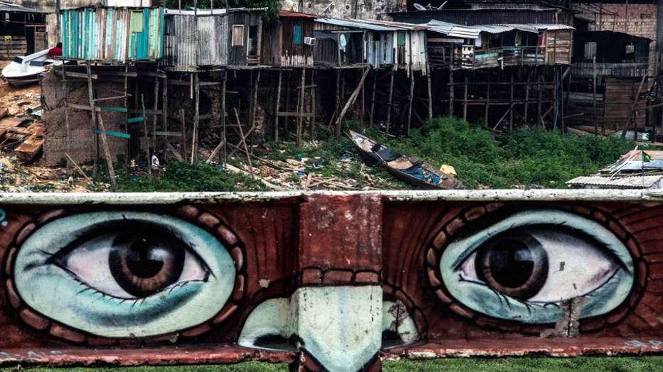 Mural é visto em um muro que separa uma favela na margem do Rio Negro, em Manaus. Foto: Christophe Simon / AFP