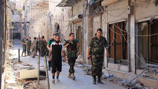 Soldados do exército sírio caminham pelas ruas de Aleppo