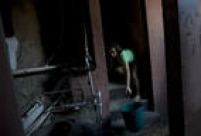 Uma menina carrega um balde de água retirada de uma bica para a sua casa, no andar superior de uma construção na Favela da Rocinha