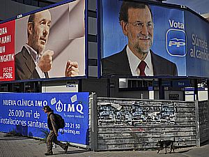 Homem caminha diante de cartazes dos candidatos Rubalcaba (&agrave; esq.) e Rajoy - Alvaro Barrientos/AP