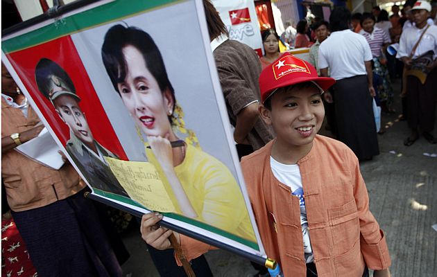 Jovem birmanesa mostra cartaz com imagem da l&iacute;der pr&oacute;-democracia Aung San Suu Kyi e de seu pai, o general Aung San