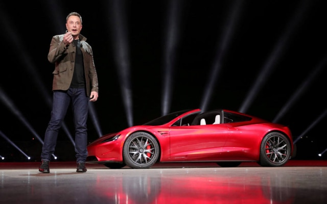 Musk e um dos carros elétricos da Tesla, que enfrenta gargalos na linha de produção
