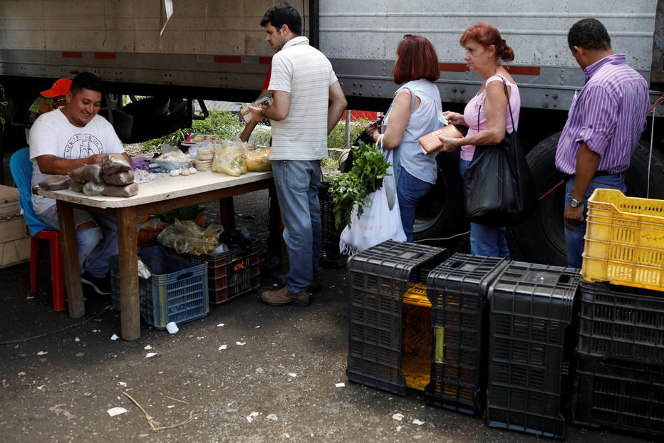 Venezuelanos compram vegetais em barraca de feirante na capital Caracas; inflação recorde corrói poder de compra no país